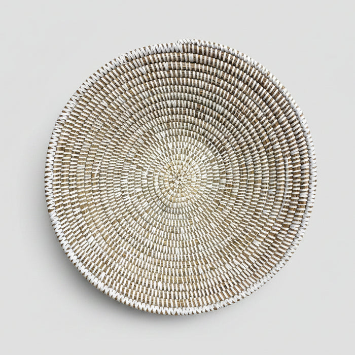 A round woven basket or tray made from natural fibers, photographed from above on a white background with a black handwritten signature reading 'La Bowl' below it.