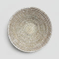 A round woven basket or tray made from natural fibers, photographed from above on a white background with a black handwritten signature reading 'La Bowl' below it.