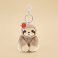 A plush sloth keychain charm with a silver metal clasp and key ring, featuring a light brown and cream sloth face with a small red circular tag.