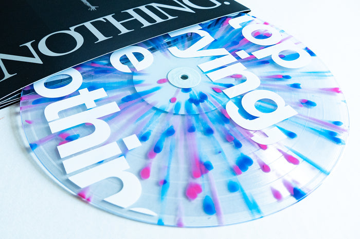 A striking Boston Manor Be Nothing 10 Year anniversary edition: a clear vinyl record with blue and pink splatters and bold white text partially visible, shown halfway out of a black-and-white sleeve with the word “NOTHING.”.