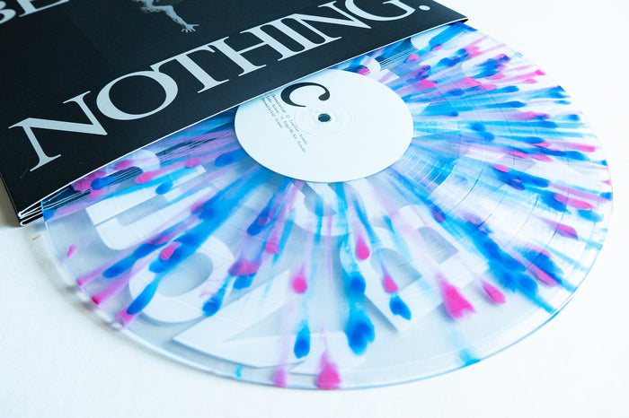 A clear vinyl with pink and blue streaks from Boston Manor's "Be Nothing" 10 Year special edition is partially displayed out of its black and white album cover labeled “NOTHING,” featuring a white center label.