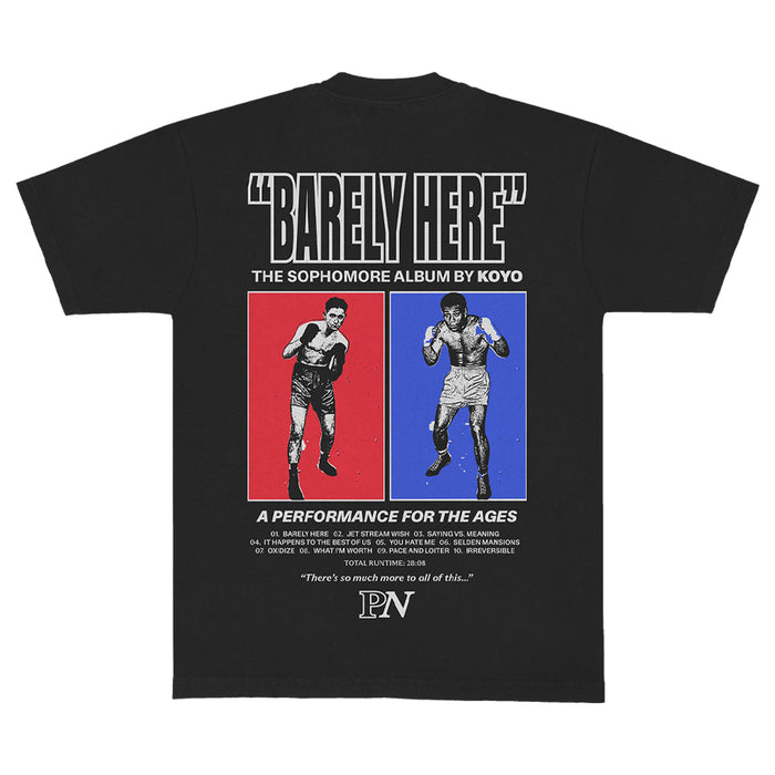 A black KOYO T-shirt with "BARELY HERE" in bold, featuring two vintage boxers in red and blue panels, text promoting KOYO's sophomore album, plus extra quotes and details underneath.