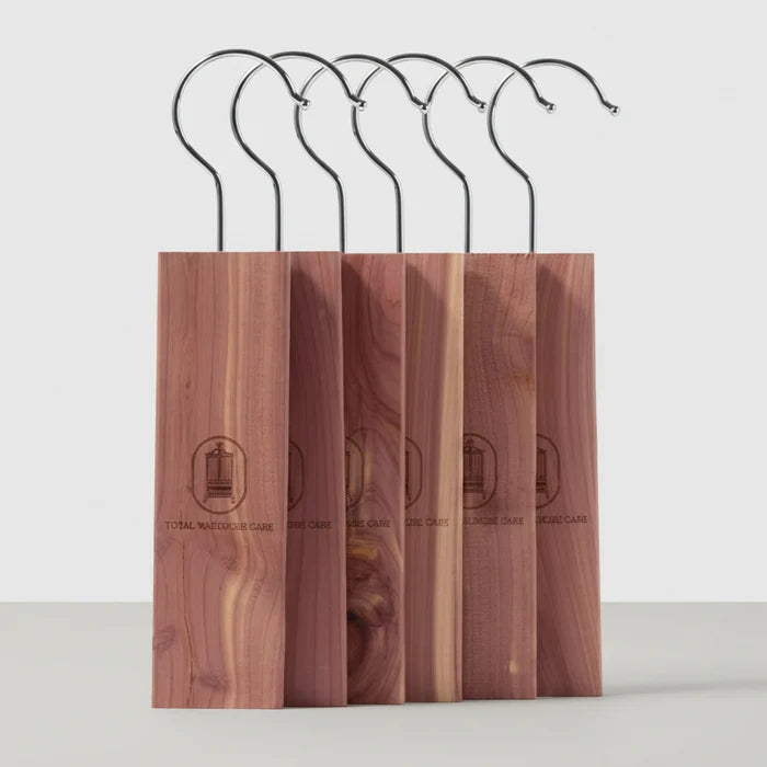 Five cedar wood bocks with black metal hooks, arranged in a row on a white background. Each stand has a vertical wood panel with a circular logo and the text 'STOCKING HANGER'.