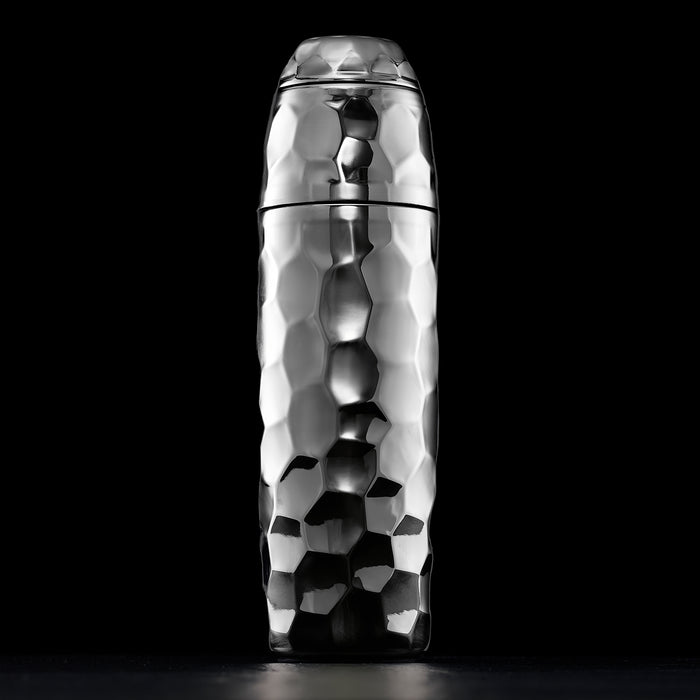 Metallic chrome, hexclad cocktail shaker with a textured surface on a black background