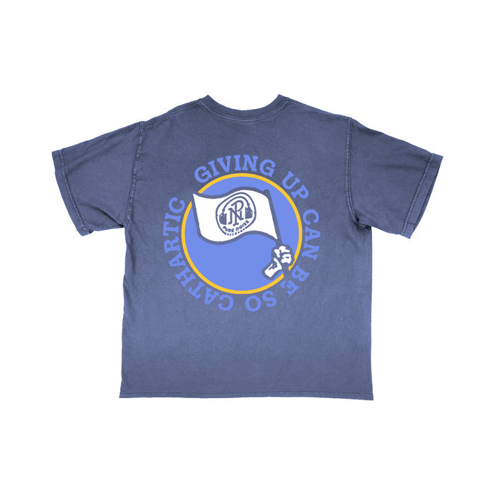 A blue Super Sometimes Comfort Colors T-shirt with a circular back graphic showing a waving white flag, logo, dollar sign, and the curved text "GIVING UP CAN BE SO CATHARTIC.