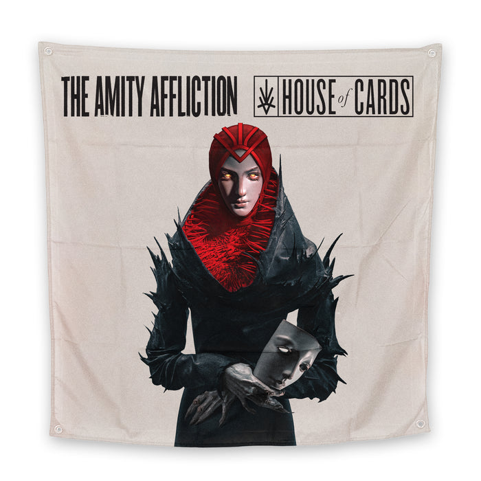 A wall tapestry by The Amity Affliction featuring "The Amity Affliction House of Cards" above a figure in a striking black and red costume, holding a human face mask against a plain, light background.