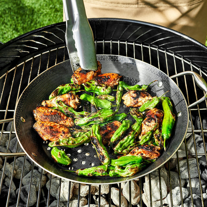 Chicken wings and green peppers being sauted in the HexClad 12&quot Hybrid BBQ Grill Pan on top of a grill