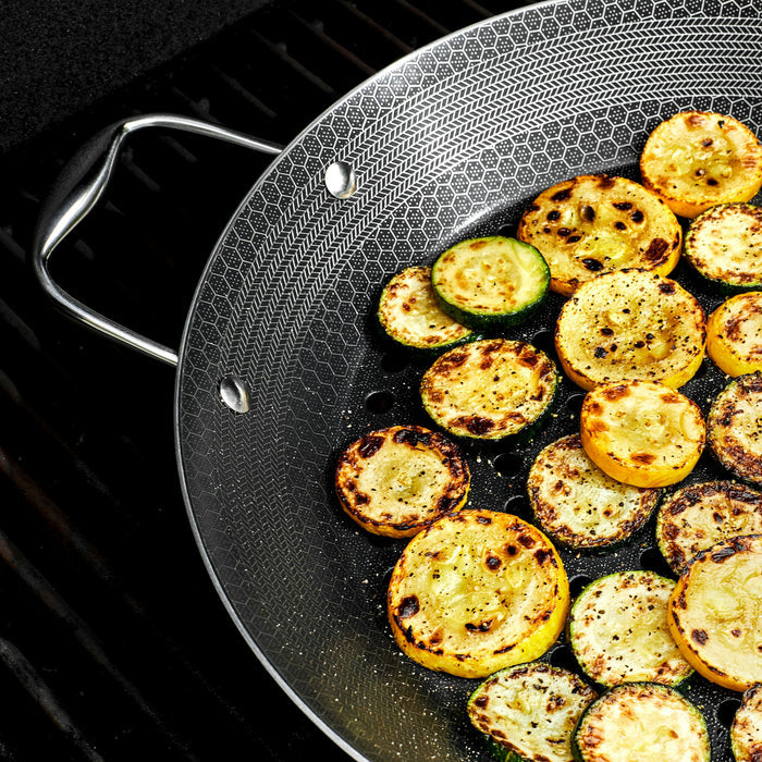 Pieces of squash and zucchini being cooked in the HexClad 12&quot Hybrid BBQ Grill Pan