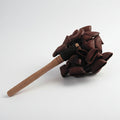 A wooden stick with a cluster of brown juju palm nuts bound at the end with twine.