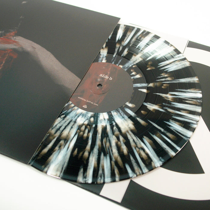 A marbled black and white vinyl from Counterparts, part of a limited edition 6th Press of only 2000, is partly pulled from its sleeve to reveal the side B label and an abstract streaked design on the disc.