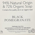 A brown cardboard box with a white label reading '94% Natural Origin & 72% Organic Soap' and 'BLACK POMEGRANATE,' photographed on a wooden surface.