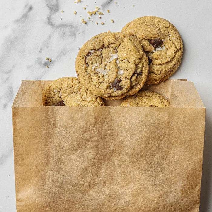 Cookies spilling out of a brown paper bag on a marble surface