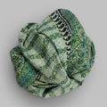 Green patterned scarf rolled up on a textured surface