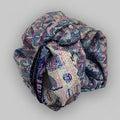 Rolled-up scarf with a blue pattern on a beige background