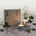 Set of three candles in front of a branded box in twilight