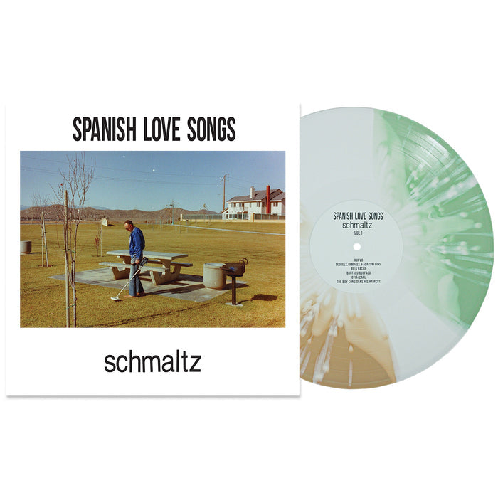 Spanish Love Songs "Schmaltz" vinyl record features a white and green swirl with white splatter. The cover shows a person by a picnic table, beer bottles, houses, and trees in the background.