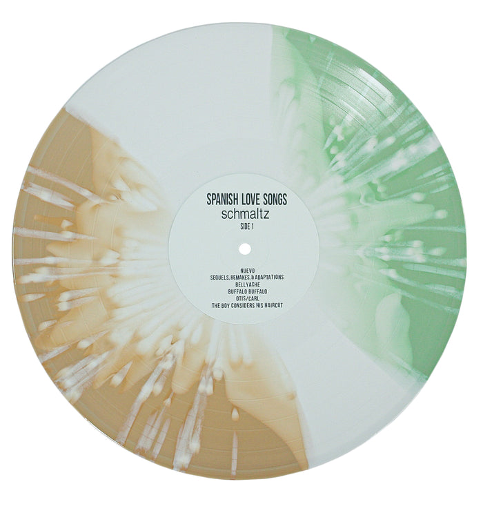 A Spanish Love Songs vinyl record featuring a white, tan, and green splatter design inspired by beer bottles. The center label reads “schmaltz Side 1” and displays song titles.