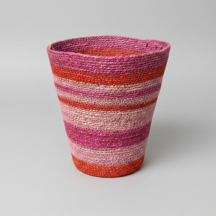 A handwoven basket with horizontal stripes of pink, red, orange, and beige.