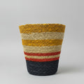 A hand-woven basket with horizontal stripes in mustard yellow, cream, red, and navy blue.
