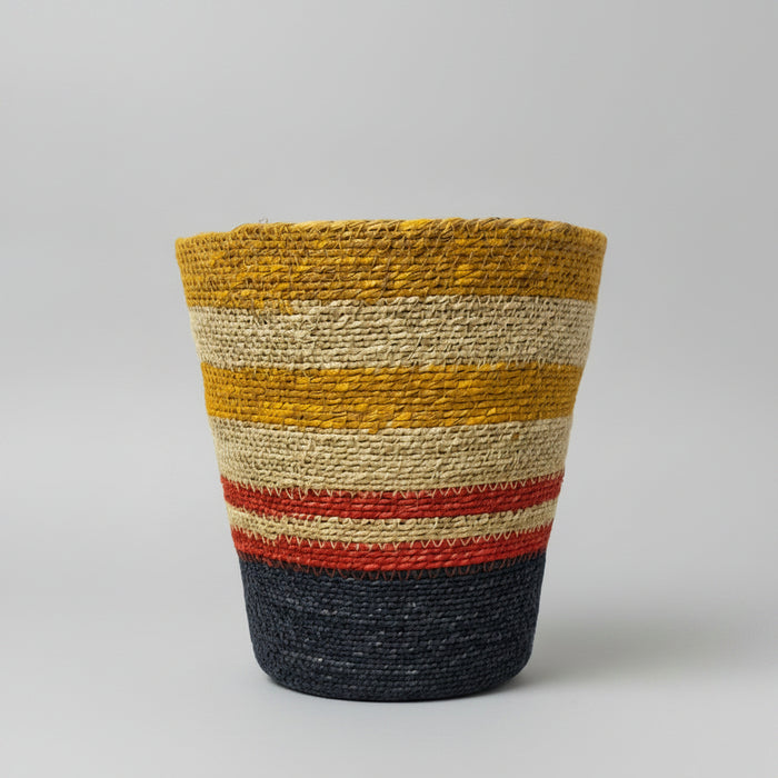 A hand-woven basket with horizontal stripes in mustard yellow, cream, red, and navy blue.