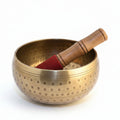 A brass singing bowl with a wooden mallet, used for relaxation and meditation.