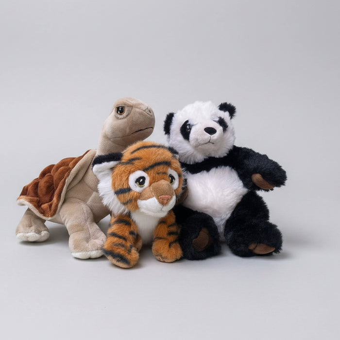 Three plush stuffed animals arranged together on a textured light green fabric background: a beige turtle with a brown shell, an orange-and-black striped tiger, and a black-and-white panda.