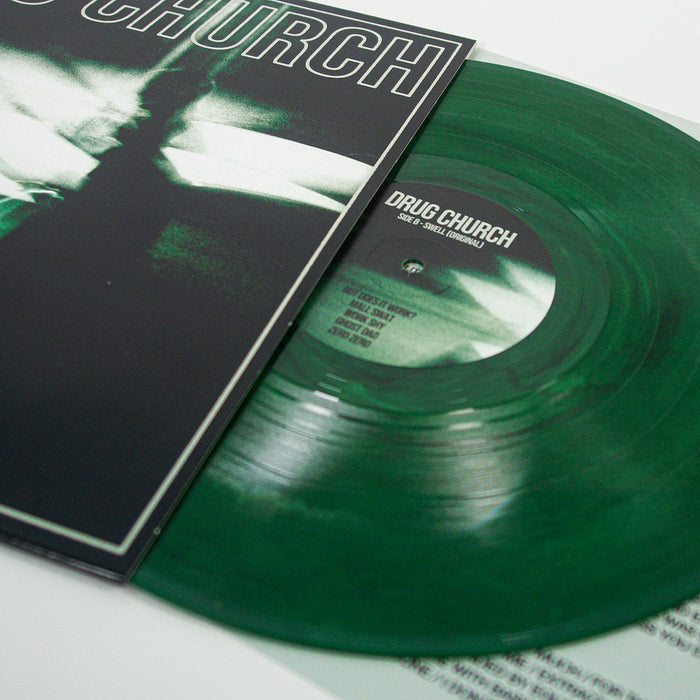 An eco green Swell Vinyl LP by Drug Church peeks from a black and white sleeve, showing the label and track list in white. Its dark album artwork features bold, stylized lettering—an ideal addition to any presale collection.