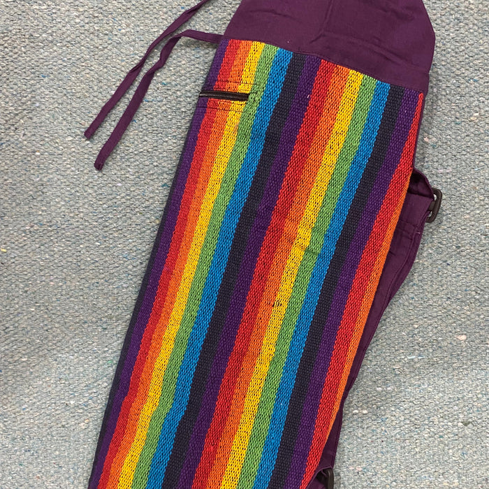 Multicolored striped yoga bag with a purple drawstring on a gray surface